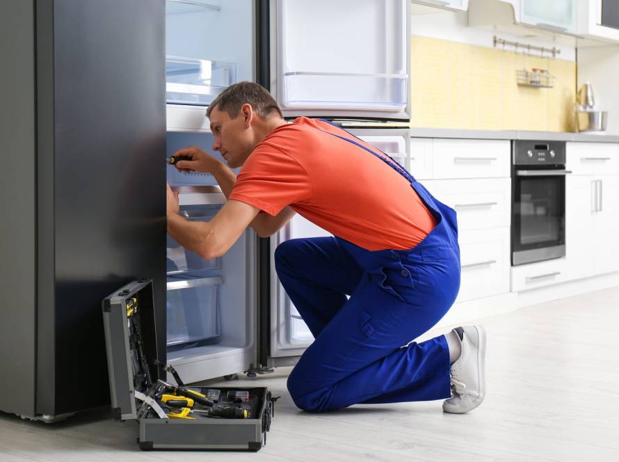 Male Technician With Screwdriver Repairing Refrigerator in Kitchen 1536x1020 1
